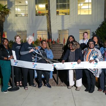 DEI team and community leaders cut ribbon in front of Black Apology plaque