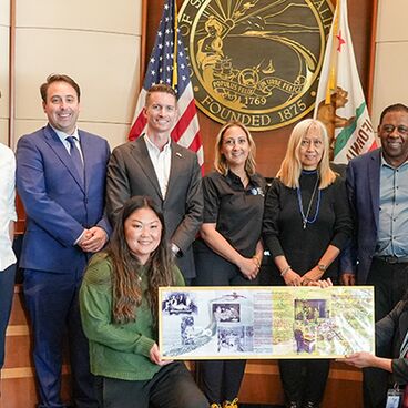 Staff and City Council stand in front of dais holding proclamation for AAPI Heritage Month 2