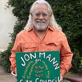 2022 Council Candidate Jonathan Mann outdoors with bike and election sign