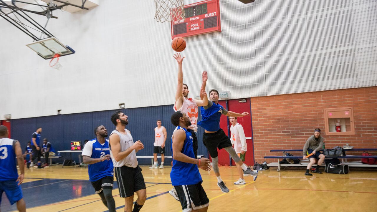 Person taking a shot at  an adult basketball league game at Memorial Park gym 
