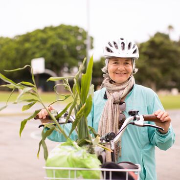 Woman Wearing a Helmet With a Plant in the Basket of Her Bike