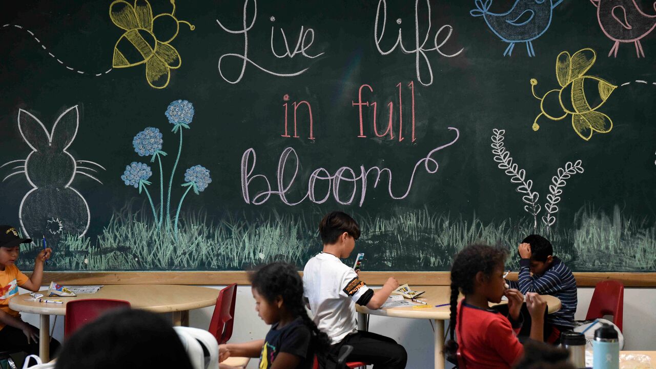 Children in classroom- spring mural background that reads "live life in full bloom"