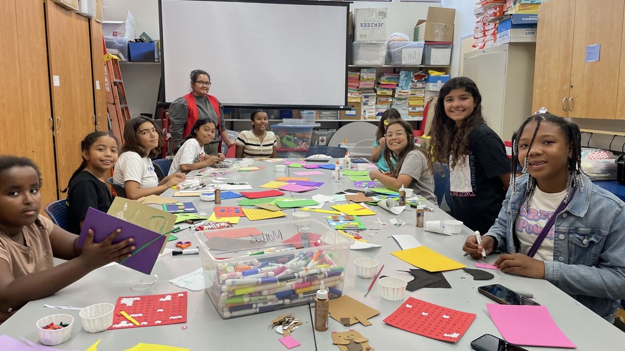 Group of girls sit around a craft table doing art projects at PAL summer camp