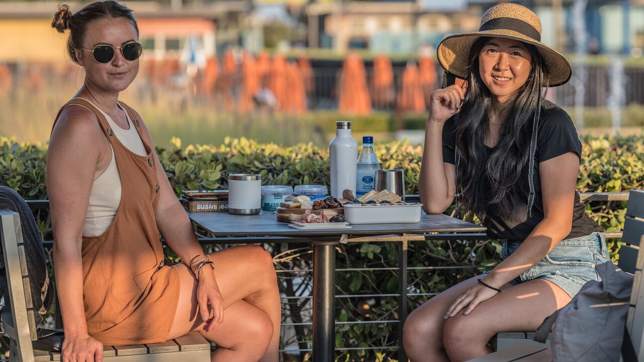 Two women sitting together eating food at the Annenberg Community Beach House for Sunset Picnic