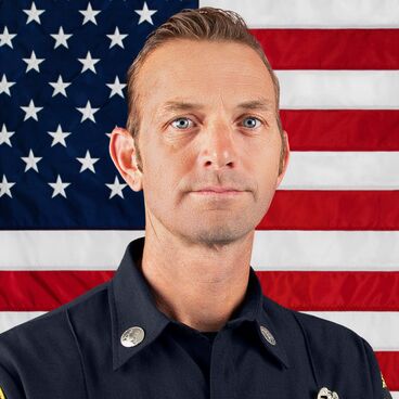 Battalion Chief Robert Erdmann in Uniform With American Flag in the Background