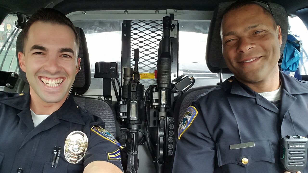 Male sworn officers in Police vehicle Smiling