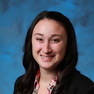 Headshot of Lauren Gold Howland Wearing a Floral Shirt and Black Blazer