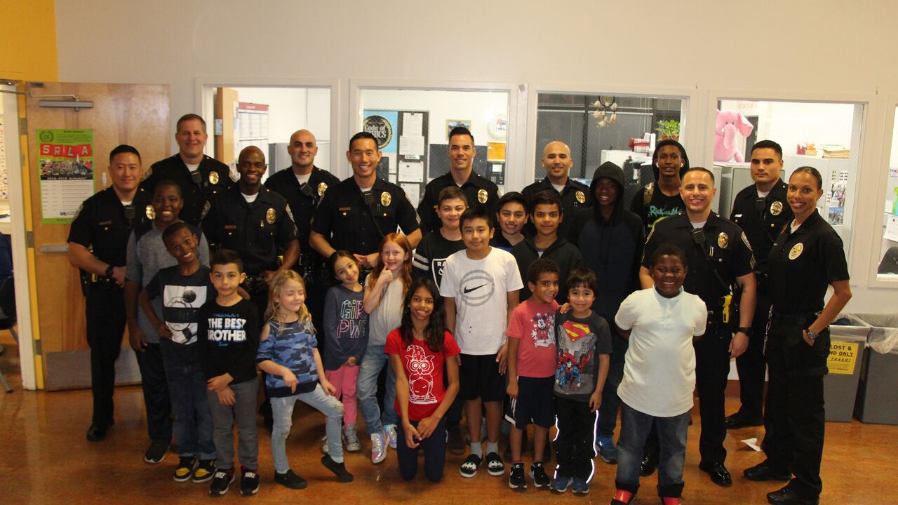 Santa Monica Police officers posing in a group photo with youth inside the Police Activities League Center