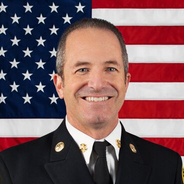 Portrait of Fire Chief Danny Alvarez with United States Flag in Background and no Hat