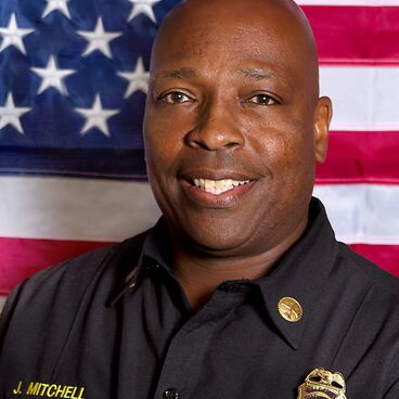 Santa Monica Fire Deputy Chief Operations Judah Mitchell Smiling in front of an American Flag