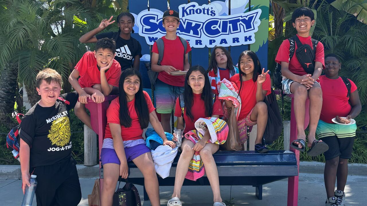 Youth in red CREST camp shirts in front of a sign at Knott's Soak City Water Park