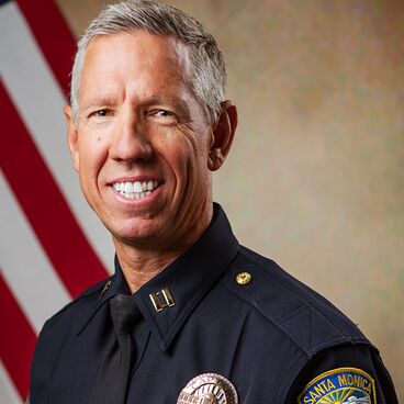 Police Captain Thomas McLaughlin in Uniform With a Flag Behind Him