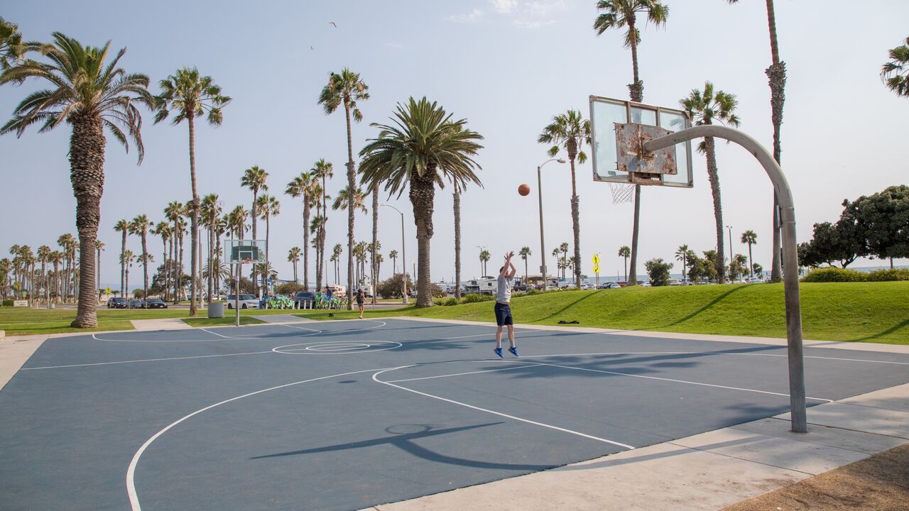 Person Playing Basketball on a Basketball Court With Palm Trees in the Background at Ocean View Park