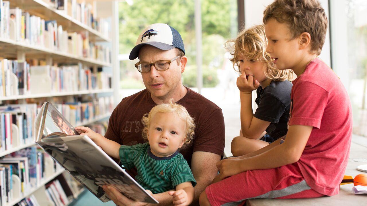 Dad Reading a Book to Three Young Kids at the Pico Branch Library