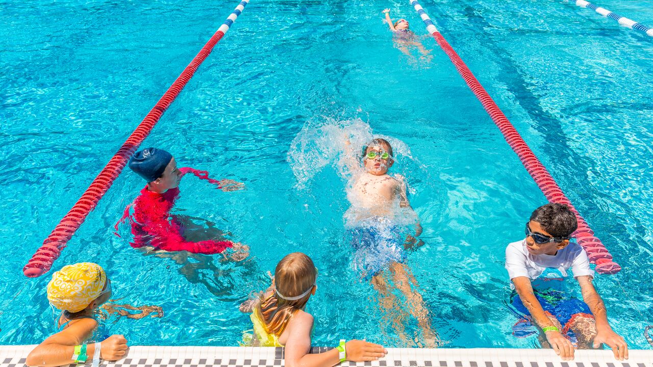 Group of Youth in a Pool With One Doing a Backstroke