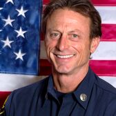 Santa Monica Fire Battalion Chief John Nevandro Smiling in front of an American Flag