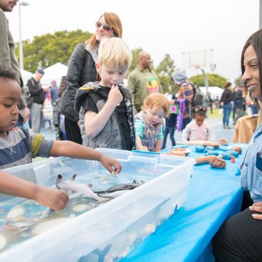 A child exploring a water activity at an event booth at Virginia Avenue Park